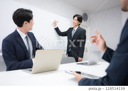 社内打ち合わせでプレゼンをするスーツを着たハンサムな男性ビジネスマン ホワイトボードの前に立つ話す 社内打ち合わせでプレゼンをするスーツを着たハンサムな男性ビジネスマン ホワイトボードの前に立つ話す 128514139