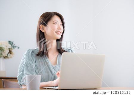 自宅の部屋でパソコンを使う若いかわいいカジュアルな服の女性　見上げる	 128515133