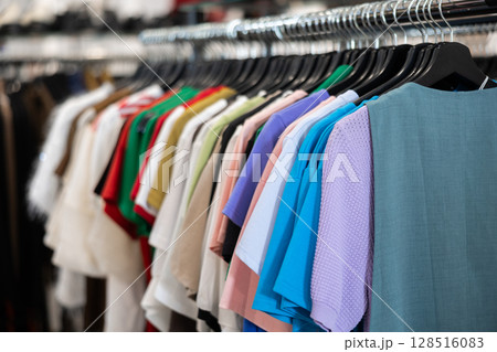 T-shirts and blouses hanging on clothes rack 128516083