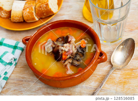 Fragrant pea soup with smoked meats and vegetables in plate 128516085