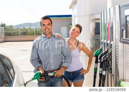 Positive couple filling up tank of their car with gasoline in gas station Positive couple filling up tank of their car with gasoline in gas station 128516098