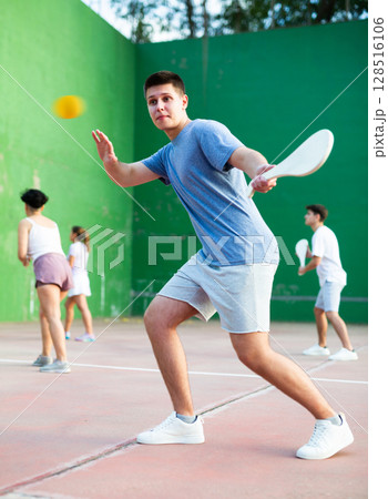 Young man with wooden paleta playing pelota goma on outdoor court 128516106