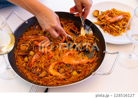 Hand holding spoon of seafood fideua Hand holding spoon of seafood fideua 128516127