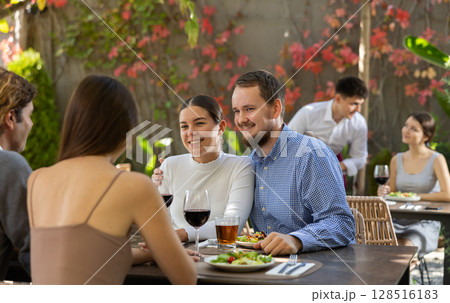 Meeting of two married couples in cozy open-air restaurant Meeting of two married couples in cozy open-air restaurant 128516183