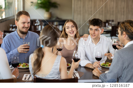 Group of friends talking and eating in restaurant 128516187