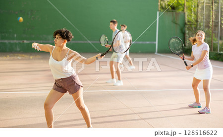 Woman playing frontenis with partners at sunny day, healthy lifestyle concept Woman playing frontenis with partners at sunny day, healthy lifestyle concept 128516622
