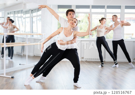 Graceful couple of ballet dancers performing supports at group class Graceful couple of ballet dancers performing supports at group class 128516767