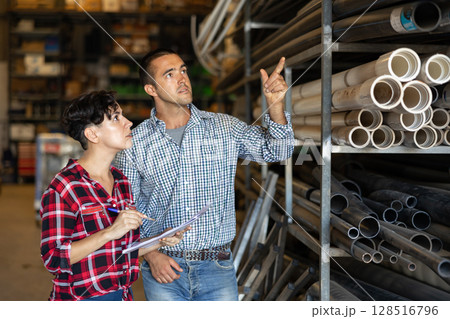 Manager and hired worker conduct an inventory in the warehouse of building materials 128516796