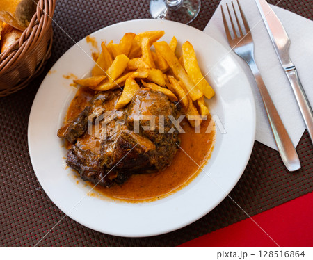 Stewed pork in broth with fried potato served in a plate Stewed pork in broth with fried potato served in a plate 128516864