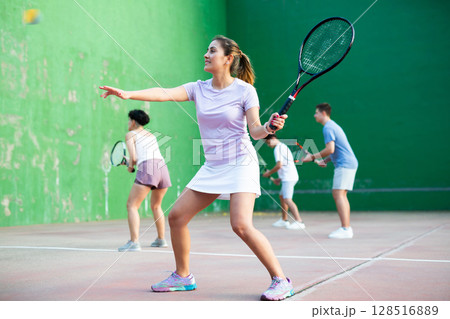Woman serving ball during frontenis game outdoors Woman serving ball during frontenis game outdoors 128516889