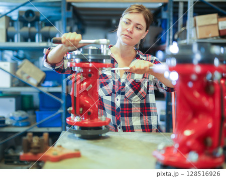 Woman assembling plumbing fixture in workshop Woman assembling plumbing fixture in workshop 128516926