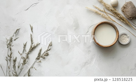 Top view of fresh milk in a wooden bowl and dry grass on white background. Top view of fresh milk in a wooden bowl and dry grass on white background. 128518225