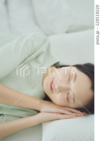 ベッドで寝ている若い女性 128519220