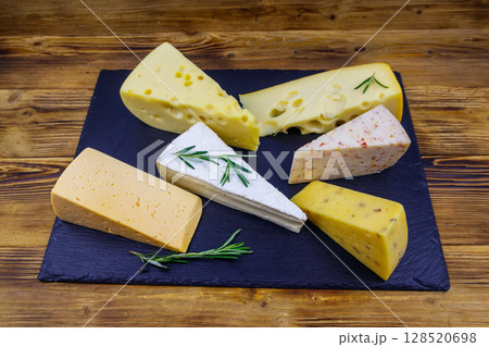 Set of various types of cheese on black slate board on a wooden table Set of various types of cheese on black slate board on a wooden table 128520698