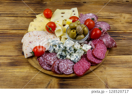 Antipasti platter with olives, cherry tomatoes, assortment of italian salami and cheese on a wooden table 128520717