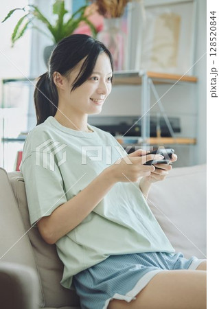 リビングでゲームをする女性 リビングでゲームをする女性 128520844