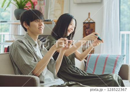 リビングでゲームをする若い夫婦 128522367