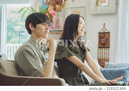 リビングでテレビを見る若い夫婦 リビングでテレビを見る若い夫婦 128522369