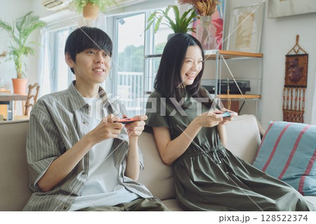 リビングでゲームをする若い夫婦 リビングでゲームをする若い夫婦 128522374