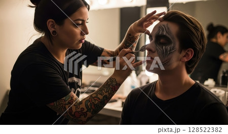 Professional makeup artist applying theatrical special effects makeup to a man face 128522382