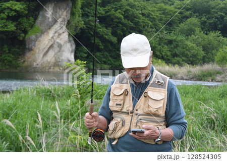 スマフォで釣り場の情報をチェックする釣り人 スマフォで釣り場の情報をチェックする釣り人 128524305