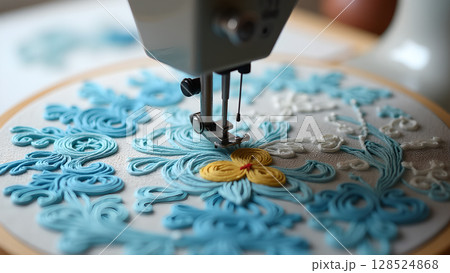 Close up of a sewing machine embroidering a beautiful pattern with blue thread and yellow flower 128524868