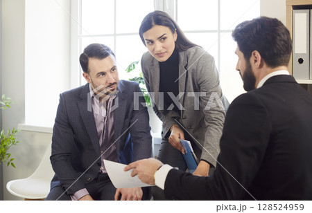 Three business people sitting in office at the workplace discussing successful deal. Three business people sitting in office at the workplace discussing successful deal. 128524959