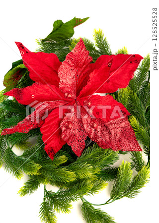 Red poinsettia flower with shiny glitter and sequins nestled in green fir branches. Elegant and festive Christmas decoration on white background. Red poinsettia flower with shiny glitter and sequins nestled in green fir branches. Elegant and festive Christmas decoration on white background. 128525528