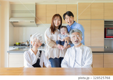 笑顔で赤ちゃんを囲む三世代家族 128525768