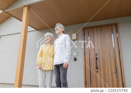 笑顔で住宅の前に立つシニアカップル 笑顔で住宅の前に立つシニアカップル 128525793