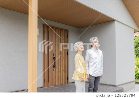 笑顔で住宅の前に立つシニアカップル 128525794