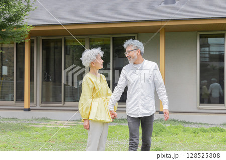 笑顔で住宅の前に立つシニア夫婦 笑顔で住宅の前に立つシニア夫婦 128525808