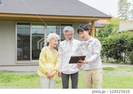 住宅の前で説明する男性作業員とシニア夫婦 128525810