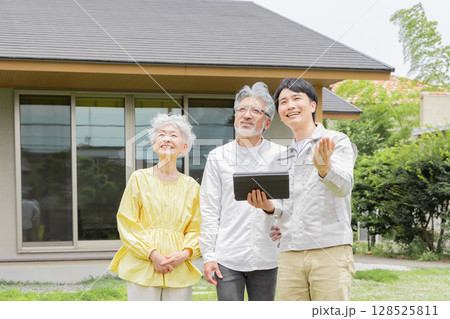 住宅の前で説明する男性作業員とシニア夫婦 128525811