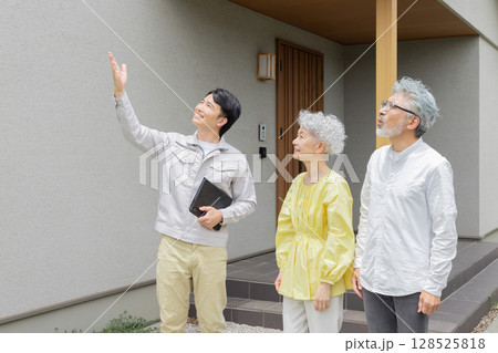 住宅の前で笑う男性作業員とシニア夫婦 128525818