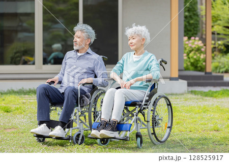 住宅の前で見上げる車椅子に乗ったシニア夫婦 住宅の前で見上げる車椅子に乗ったシニア夫婦 128525917