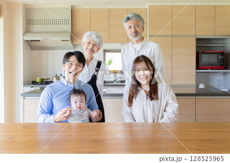 赤ちゃんを囲んで喜ぶ三世代家族の集合写真 128525965