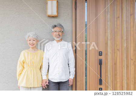 笑顔で住宅の前に立つシニアカップル 128525982