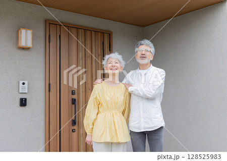 笑顔で住宅の前に立つシニアカップル 128525983