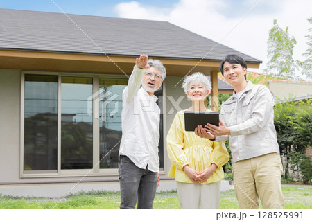 住宅の前で説明する男性作業員とシニア夫婦 128525991