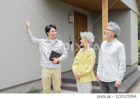 住宅の前で笑う男性作業員とシニア夫婦 128525994