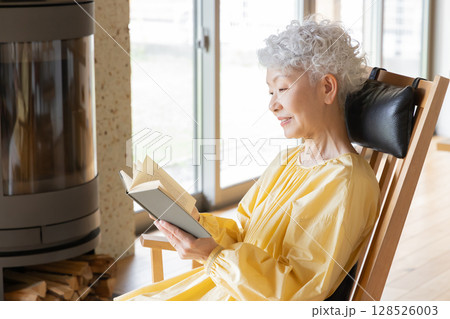 ロッキングチェアに座って読書をするシニア女性 128526003