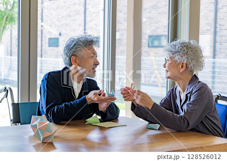 折り紙をする車椅子に乗ったシニア男女 128526012