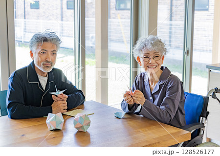折り紙をする車椅子に乗ったシニア男女 128526177