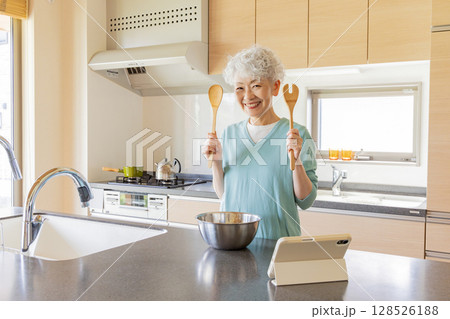 タブレットを見ながら料理するシニア女性 128526188