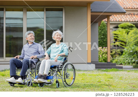 住宅の前で見上げる車椅子に乗ったシニア夫婦 住宅の前で見上げる車椅子に乗ったシニア夫婦 128526223