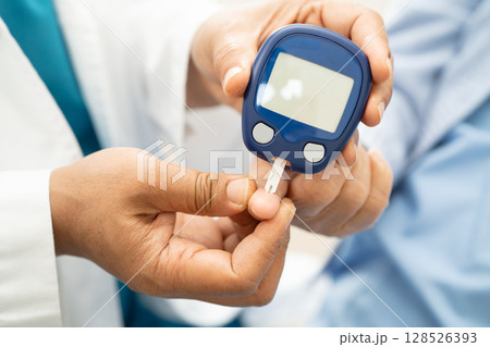 Doctor check diabetes from finger blood sugar level with finger lancet. 128526393