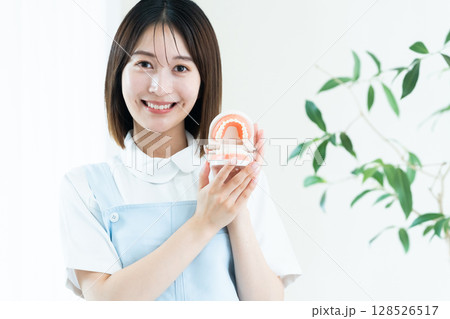 歯の模型を持つ歯科スタッフの女性 128526517