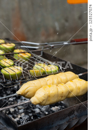 Chopped zucchini and khachapuri roasting on fire seasoned with aroma herbs and spices. Delicious fresh vegetables vegetarian grilling on barbecue smoker grid. Diet vegan bbq. Outdoor recreation 128527074
