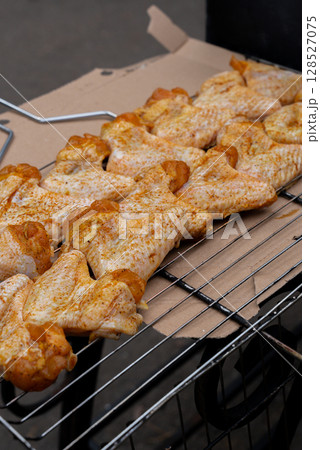 Delicious chicken frying on barbecue grill grate outdoor. Seasoning falling on fresh grilled chicken wings. Summer party food ideas. BBQ Juicy roasting chicken grill legs Delicious chicken frying on barbecue grill grate outdoor. Seasoning falling on fresh grilled chicken wings. Summer party food ideas. BBQ Juicy roasting chicken grill legs 128527075